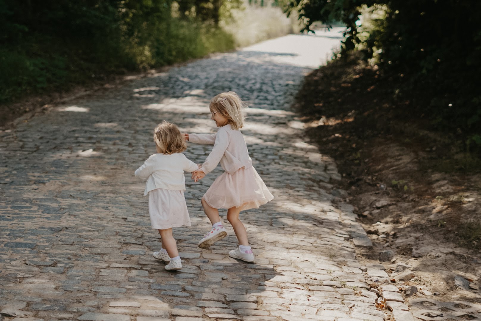 Reviews & Kind Words. Zusjes hand in hand op de foto tijdens een familieshoot door een gezinsfotograaf